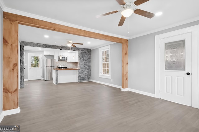 unfurnished living room featuring crown molding, ceiling fan, and dark hardwood / wood-style floors