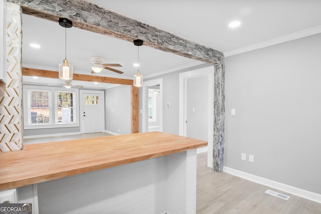 kitchen with wood counters, decorative light fixtures, light hardwood / wood-style floors, ceiling fan, and ornamental molding