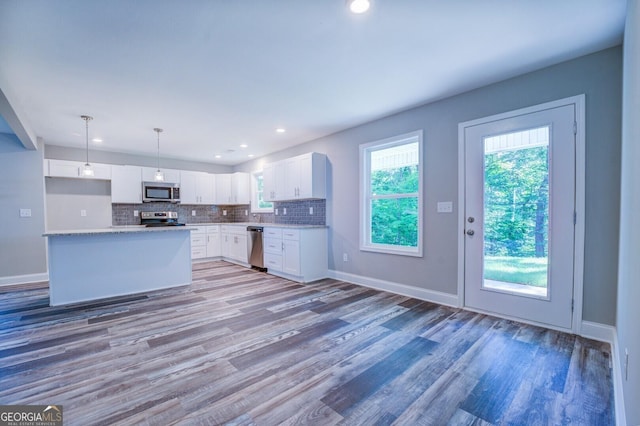 kitchen with hardwood / wood-style floors, decorative light fixtures, tasteful backsplash, white cabinets, and stainless steel appliances