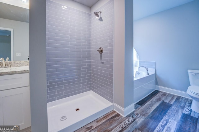 full bathroom featuring wood-type flooring, separate shower and tub, vanity, and toilet