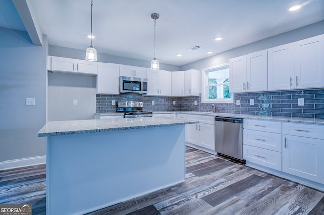 kitchen with white cabinetry, light stone counters, a kitchen island, pendant lighting, and stainless steel appliances