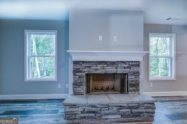 interior details with wood-type flooring and a stone fireplace