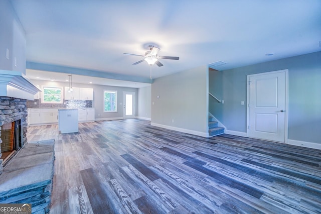 unfurnished living room with dark hardwood / wood-style flooring, ceiling fan, and a fireplace