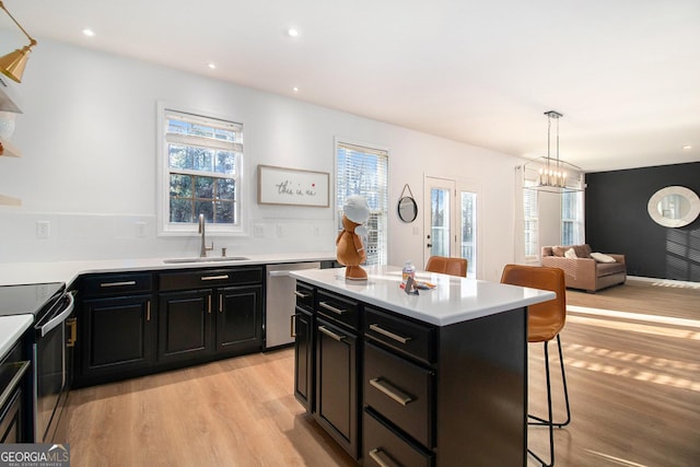 kitchen with sink, appliances with stainless steel finishes, hanging light fixtures, a center island, and a kitchen bar