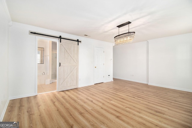 interior space featuring a barn door, a notable chandelier, and light hardwood / wood-style flooring