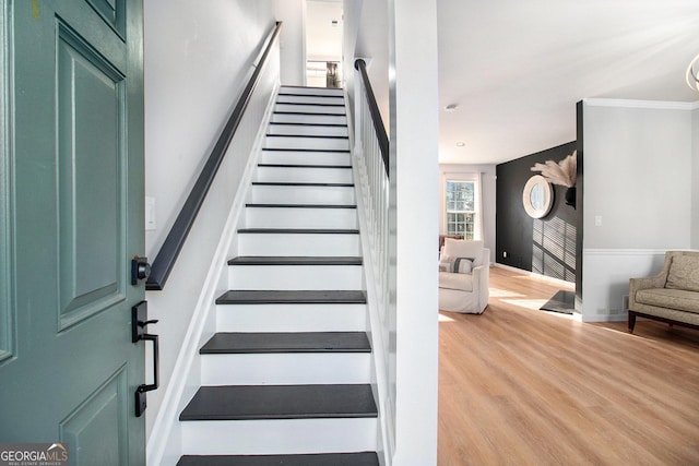 stairs featuring hardwood / wood-style flooring and crown molding