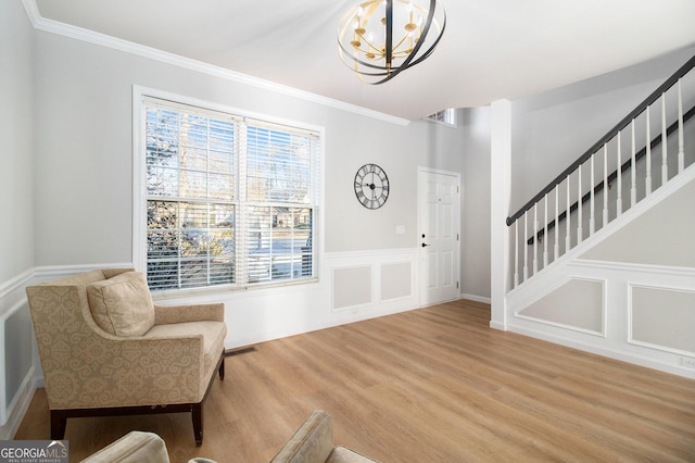 sitting room featuring hardwood / wood-style flooring, ornamental molding, and a chandelier