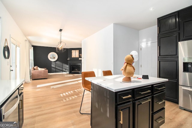 kitchen with appliances with stainless steel finishes, pendant lighting, a breakfast bar area, a center island, and light wood-type flooring