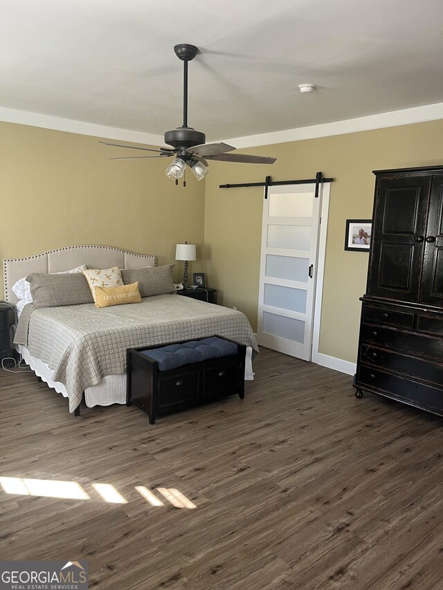 bedroom with dark hardwood / wood-style flooring, a barn door, crown molding, and ceiling fan