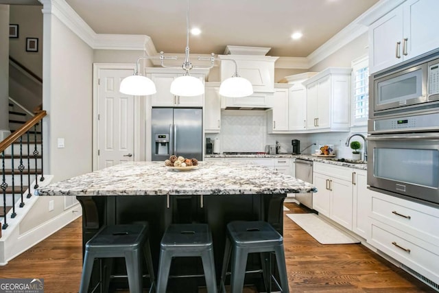 kitchen featuring stainless steel appliances, a kitchen island, white cabinets, and decorative light fixtures