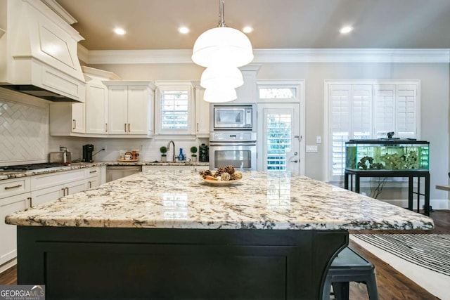 kitchen with a kitchen island, appliances with stainless steel finishes, pendant lighting, sink, and custom exhaust hood