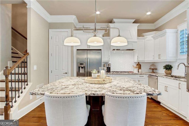 kitchen with pendant lighting, sink, stainless steel appliances, a center island, and light stone counters