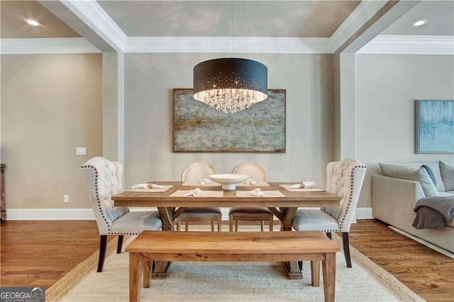 dining room with crown molding, hardwood / wood-style floors, and a notable chandelier