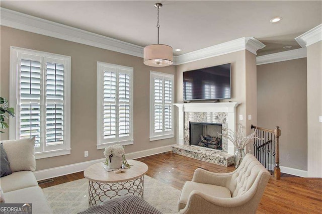 living room with a fireplace, plenty of natural light, ornamental molding, and wood-type flooring