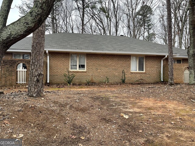 view of property exterior with a shingled roof and brick siding