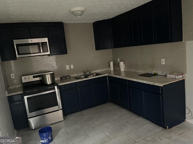 kitchen with dark cabinets, appliances with stainless steel finishes, light countertops, and a sink