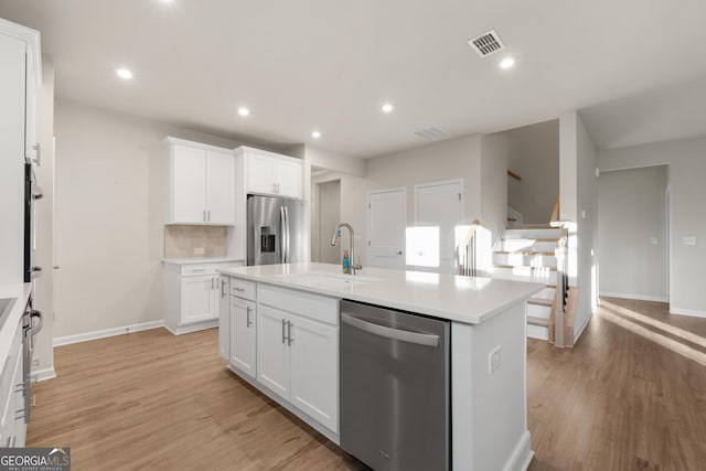 kitchen featuring sink, white cabinetry, an island with sink, stainless steel appliances, and light hardwood / wood-style floors