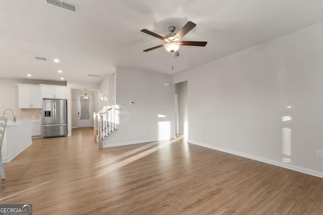 unfurnished living room with wood-type flooring, sink, and ceiling fan