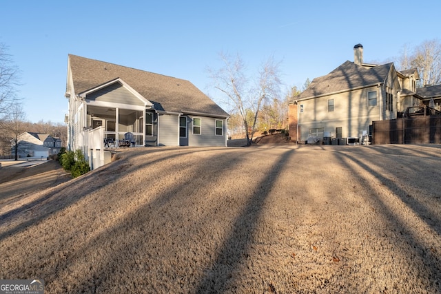 rear view of house featuring a sunroom and a lawn