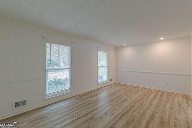 unfurnished room featuring ornamental molding, a textured ceiling, and light hardwood / wood-style flooring