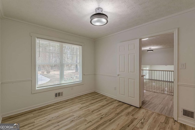 unfurnished room with ornamental molding, light hardwood / wood-style floors, and a textured ceiling