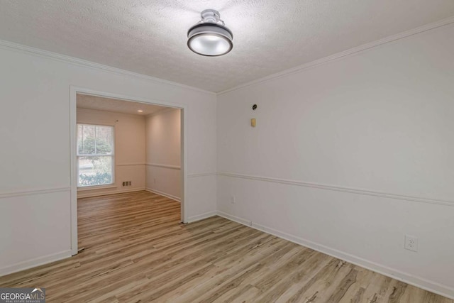 empty room with ornamental molding, a textured ceiling, and light hardwood / wood-style floors