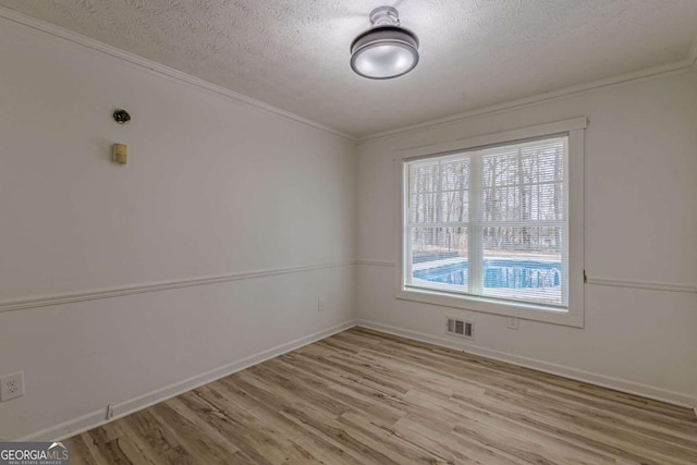 unfurnished room featuring light hardwood / wood-style flooring, ornamental molding, and a textured ceiling