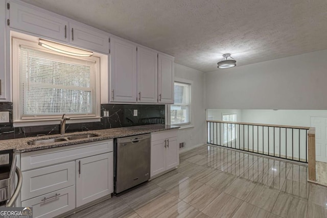 kitchen with white cabinetry, dishwasher, sink, and dark stone counters