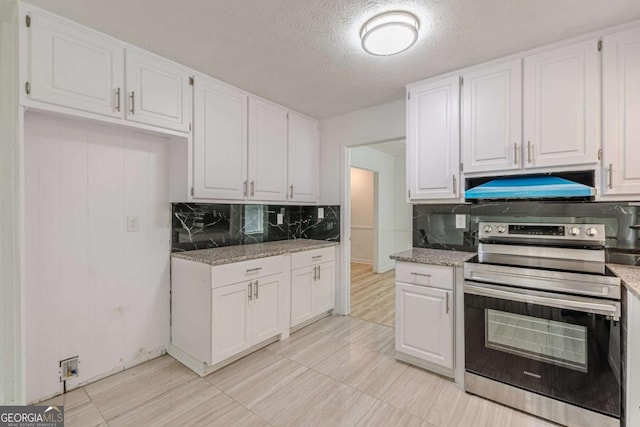 kitchen with light stone counters, decorative backsplash, stainless steel range with electric cooktop, and white cabinets