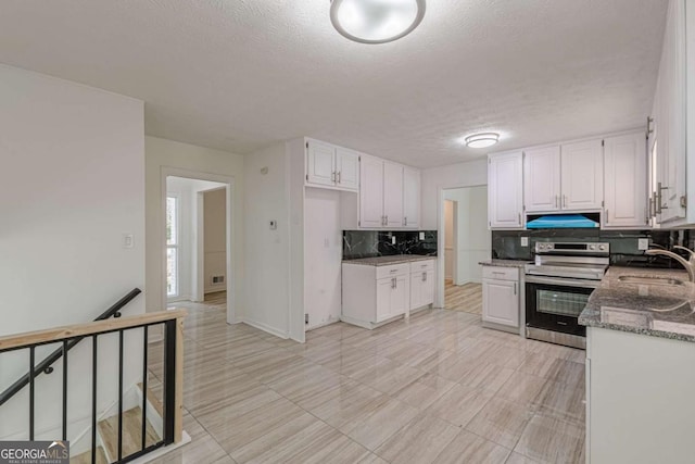 kitchen featuring sink, dark stone countertops, electric range, white cabinets, and decorative backsplash