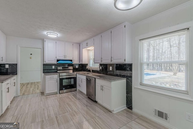 kitchen with sink, dark stone countertops, backsplash, stainless steel appliances, and white cabinets