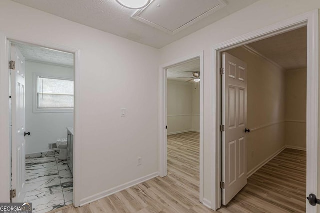 corridor with a textured ceiling and light hardwood / wood-style floors