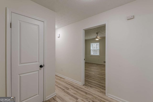 hall with a textured ceiling and light wood-type flooring