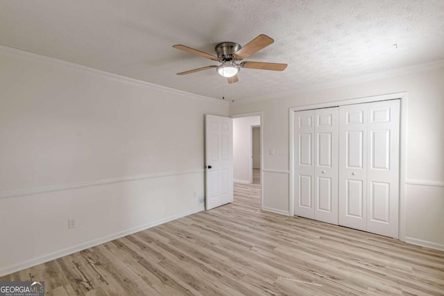 unfurnished bedroom featuring light wood-type flooring, ornamental molding, ceiling fan, a textured ceiling, and a closet