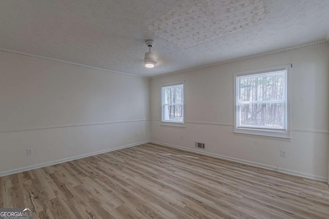 empty room with a textured ceiling and light wood-type flooring