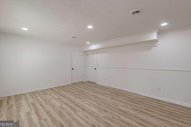 spare room with a textured ceiling and light hardwood / wood-style flooring