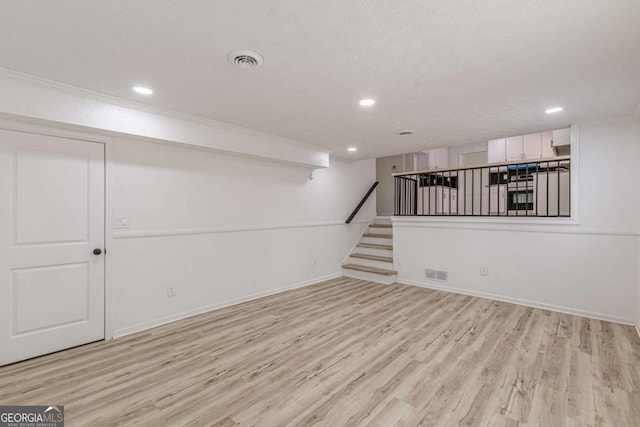 basement featuring light hardwood / wood-style flooring and a textured ceiling