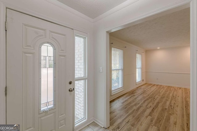 entrance foyer featuring crown molding, a textured ceiling, and light wood-type flooring