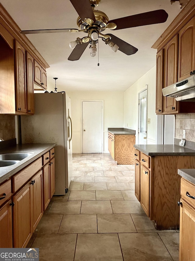 kitchen with tasteful backsplash, ceiling fan, sink, and white fridge