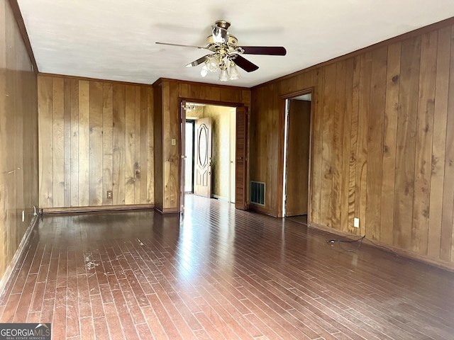 empty room featuring dark wood-type flooring, ceiling fan, and wooden walls