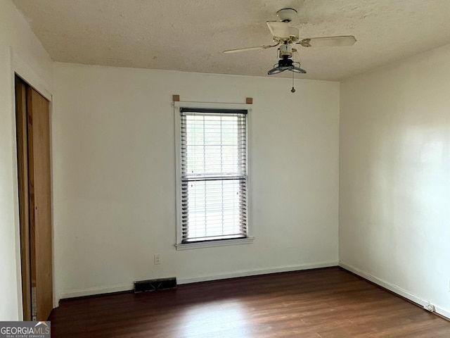 empty room with ceiling fan, dark hardwood / wood-style floors, and a textured ceiling