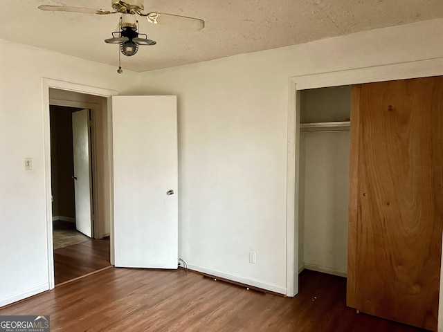 unfurnished bedroom featuring ceiling fan, dark wood-type flooring, a textured ceiling, and a closet