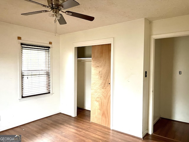 unfurnished bedroom with ceiling fan, wood-type flooring, a closet, and a textured ceiling