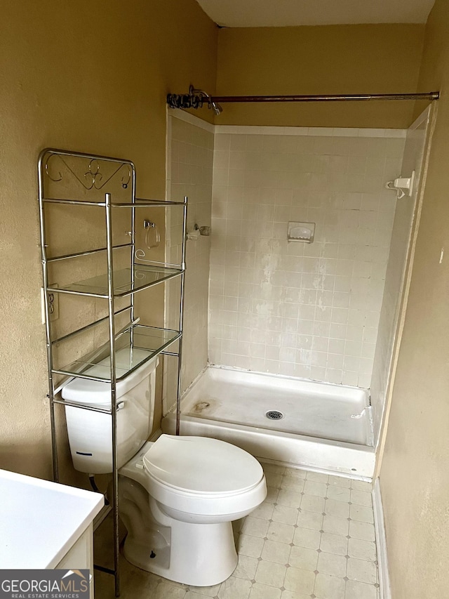 bathroom featuring vanity, toilet, and tiled shower