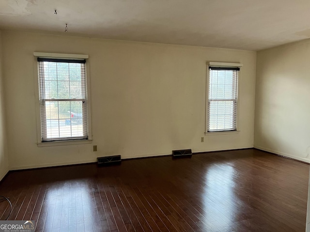 empty room featuring plenty of natural light and dark hardwood / wood-style floors