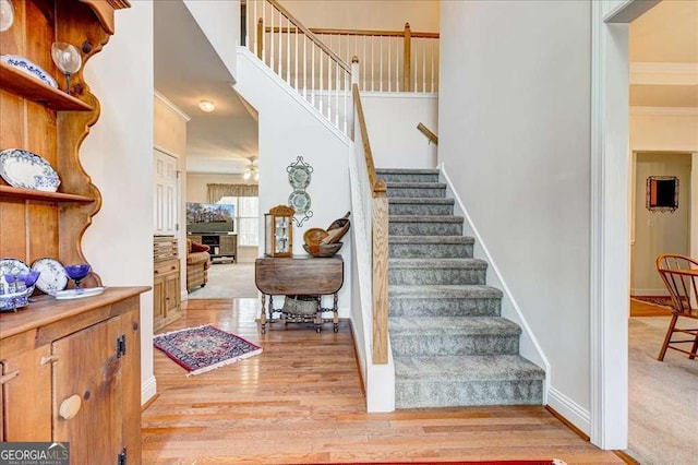 entryway with a high ceiling, crown molding, ceiling fan, and light hardwood / wood-style floors