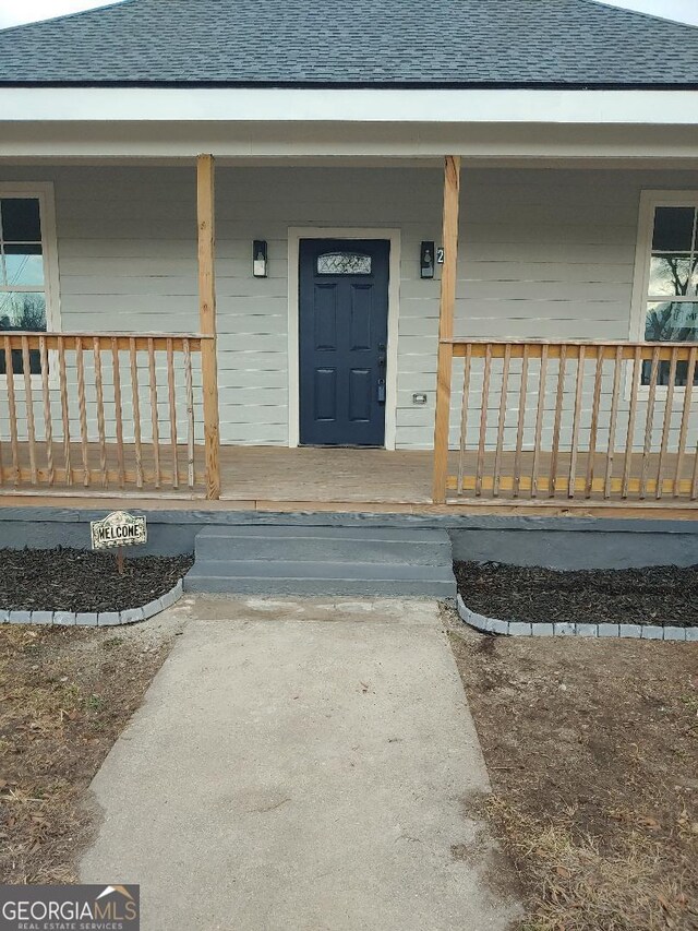 view of exterior entry featuring covered porch