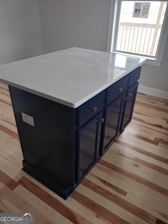 kitchen featuring blue cabinetry, a kitchen island, and light hardwood / wood-style flooring