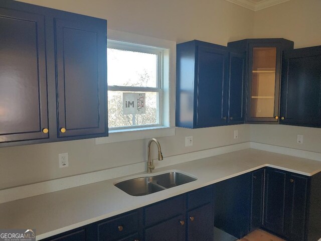 kitchen with sink, crown molding, light wood-type flooring, and a kitchen island