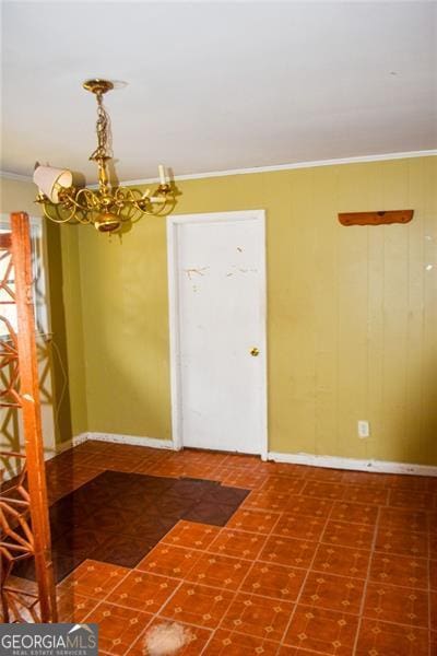 spare room with ornamental molding and a chandelier